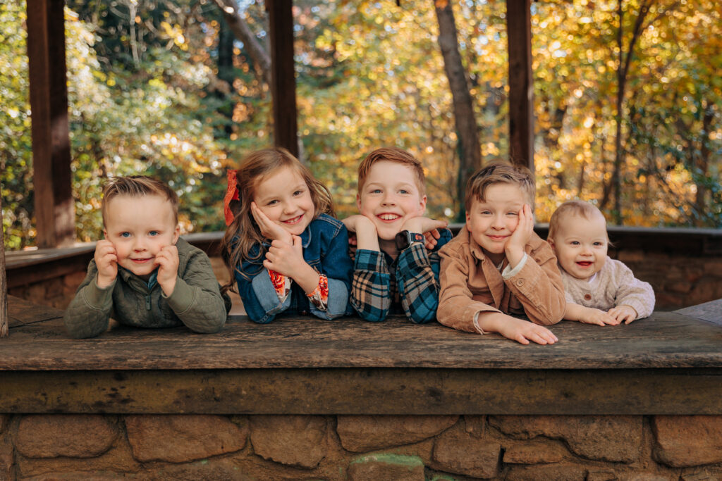 fall family photo of 5 kids from baby to toddler to preschool age to grade school age all smile for family photo