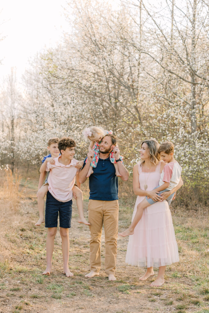 spring family photo with four kids on a trail with flowering trees near Hendersonville, North Carolina by Asheville photographer Rachel Marie Photography