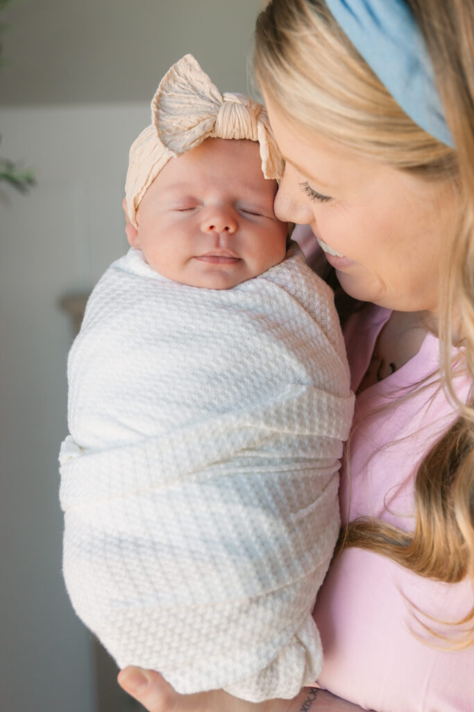 mom holds swaddled newborn baby girl during an in-home newborn session in Hendersonville, NC with family photographer Rachel Marie Photography