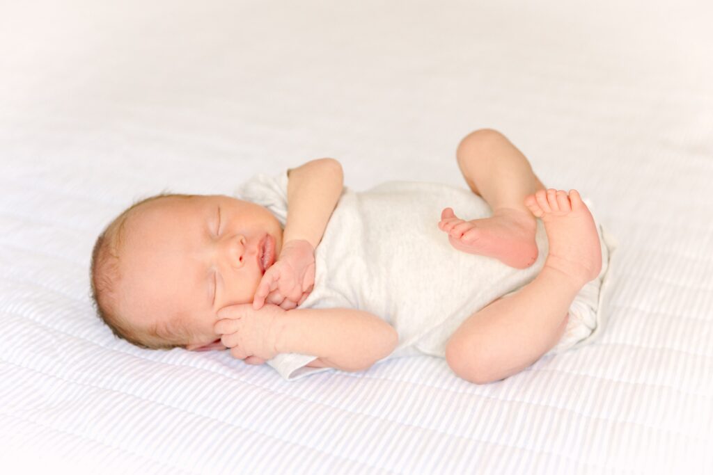 newborn baby boy sleeping in a onesie on a soft bed during newborn portraits with Asheville Newborn Photographer Rachel Marie Photography
