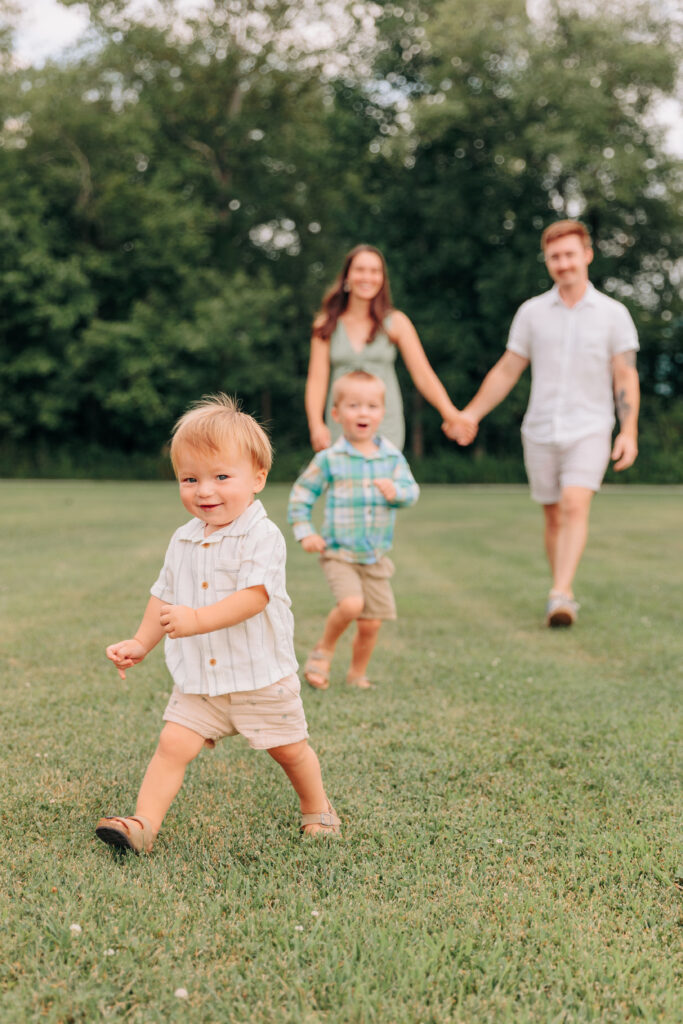 Family with two toddlers are running around and playing at the park during fun family photo session with Rachel Marie Photography in Hendersonville, NC