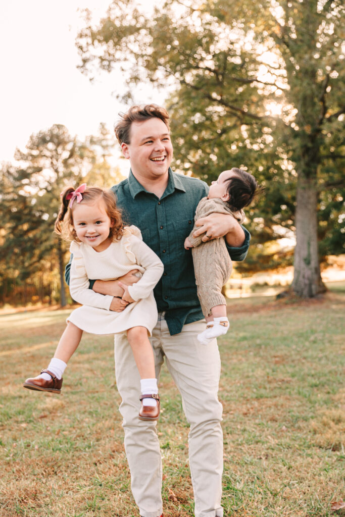 dad laughing and holding toddler and baby during family photo session with Asheville Family Photographer Rachel Marie Photography