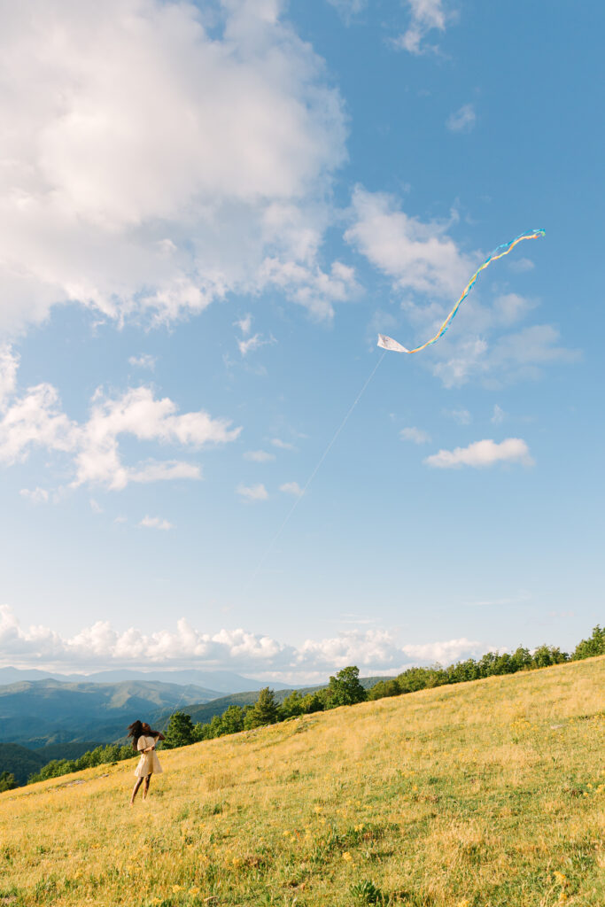 girl flying kite at bear wallow mountain, sunset mountain view family adventure photo session at Bear Wallow Mountain in Hendersonville, NC with family of two teenagers