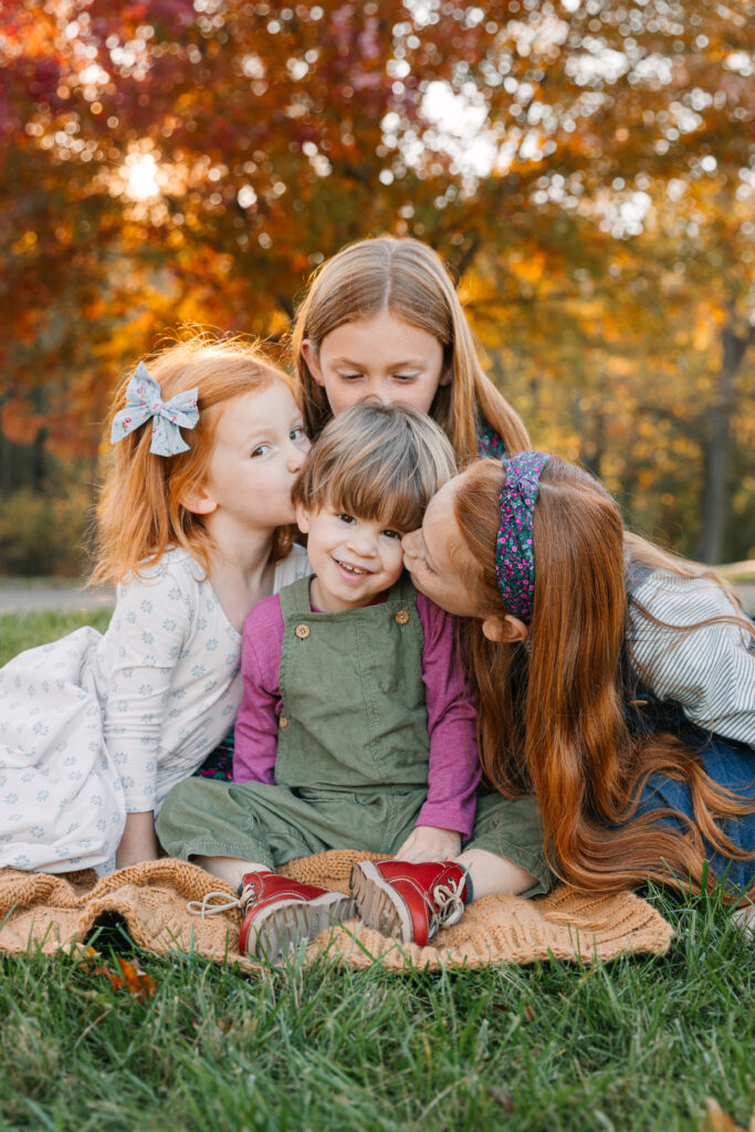 Three sisters kissing baby brother during Fall Family Photo Session with Asheville, Photographer Rachel Marie Photography