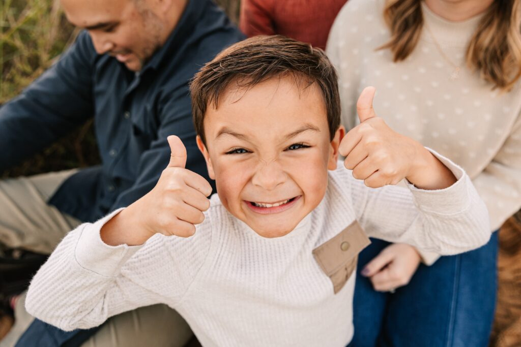 Little boy smiles with two thumbs up for fall family photo session with Asheville Photographer, Rachel Marie Photography
