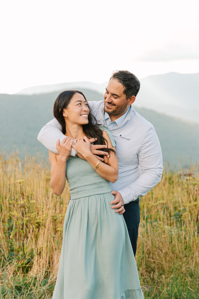 couple poses together smiling at each other at the top of black balsam knob near Asheville, NC with family photographer Rachel Marie Photography