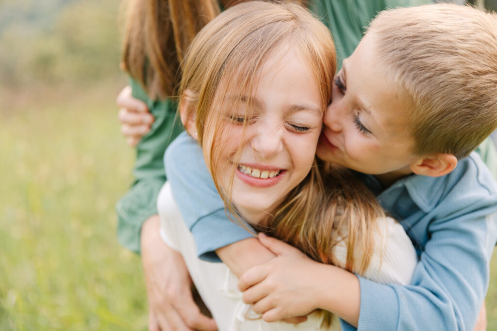 a brother kissing a sister on the cheek during a family photo session at the Biltmore Estate in Asheville, NC 