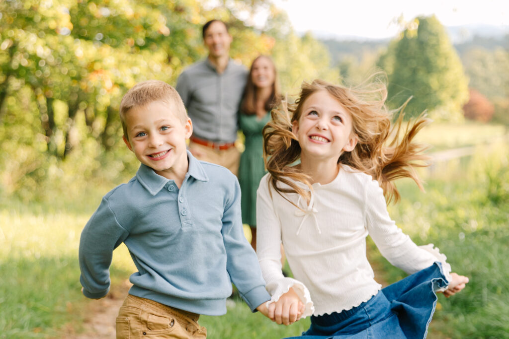 a brother and sister dancing and smiling during a family photo session at the Biltmore Estate in Asheville, NC