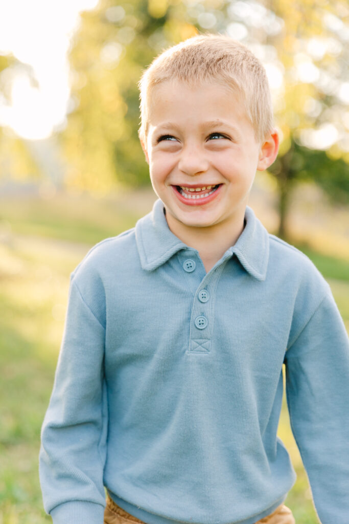 a little boy laughing and looking off camera during a family photo session at the Biltmore Estate in Asheville, NC