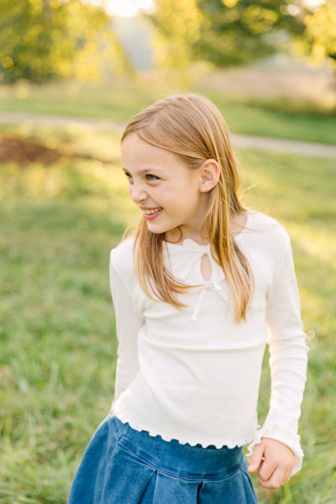 a little girl laughing and looking off camera during a family photo session at the Biltmore Estate in Asheville, NC