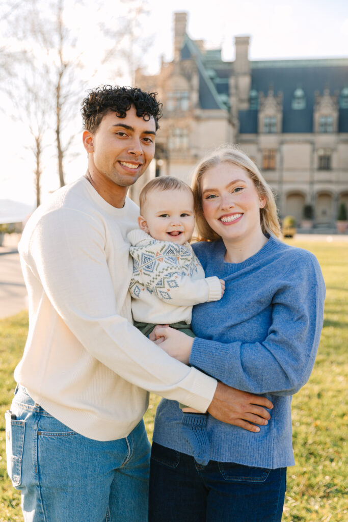 Family of three smiling for a photo in front of the Biltmore House.