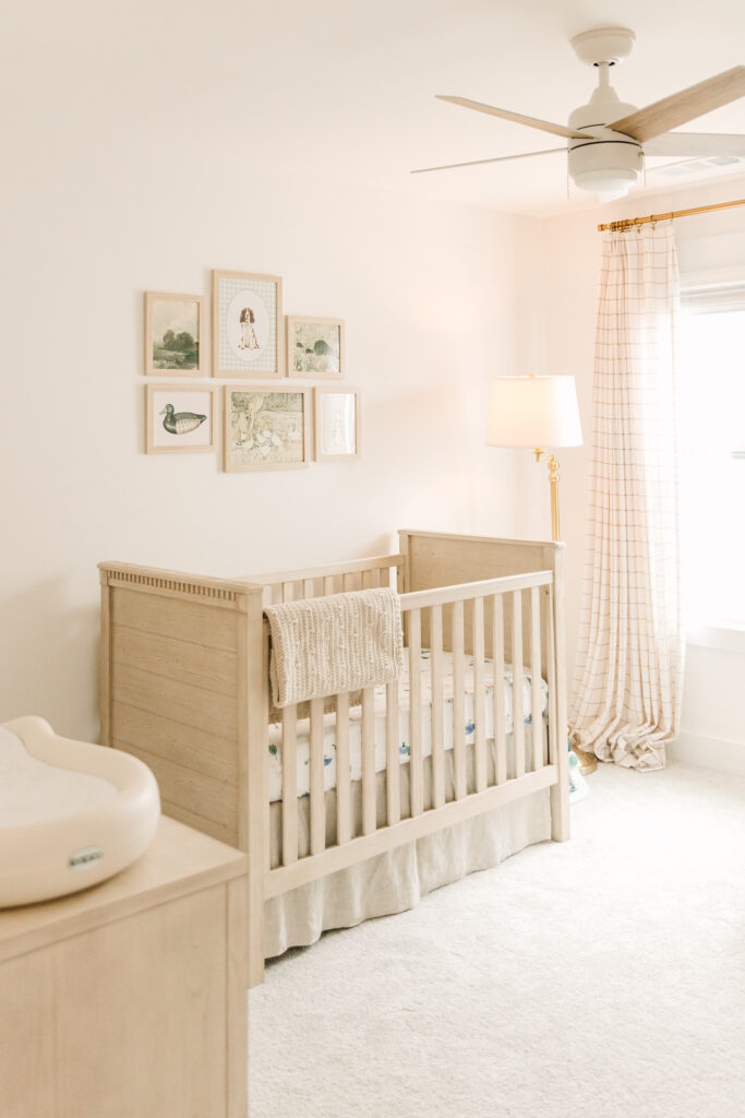 Newborn room with neutral colors and a gallery of photos on the wall.