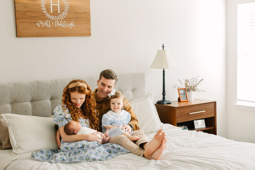 family snuggles on bed with toddler daughter and newborn son during in-home newborn session with Asheville Newborn Photographer Rachel Marie Photography
