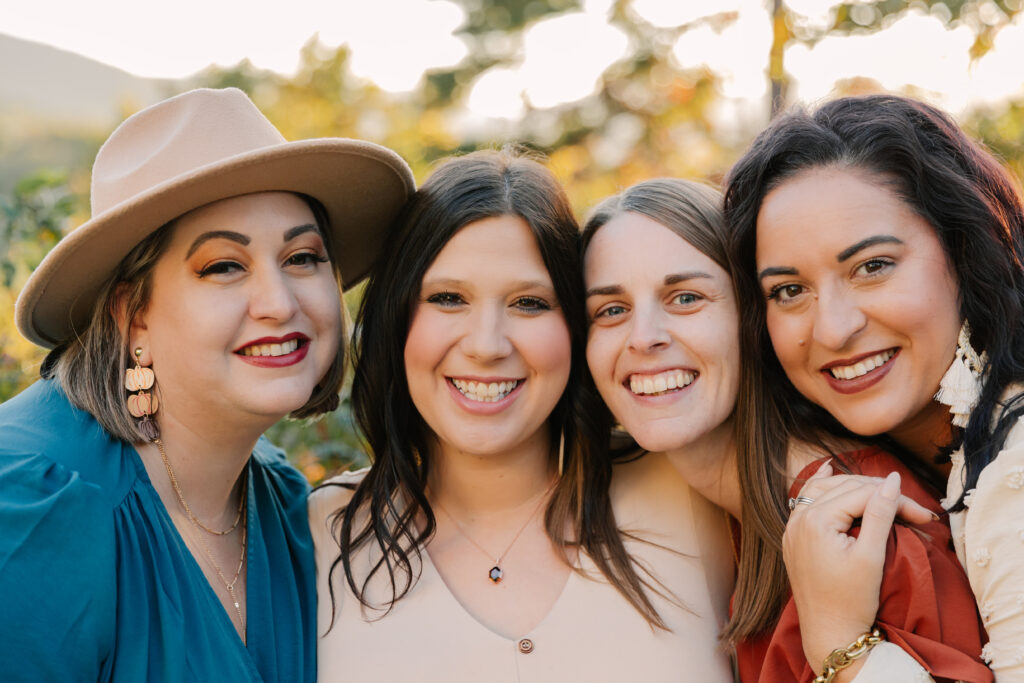 Four sisters smile together during extended family photo session in Asheville, NC with family photographer Rachel Marie Photography