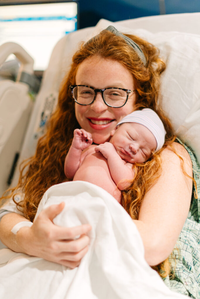 mother smiles while holding newborn baby boy just after delivery at mission hospital in Asheville, NC