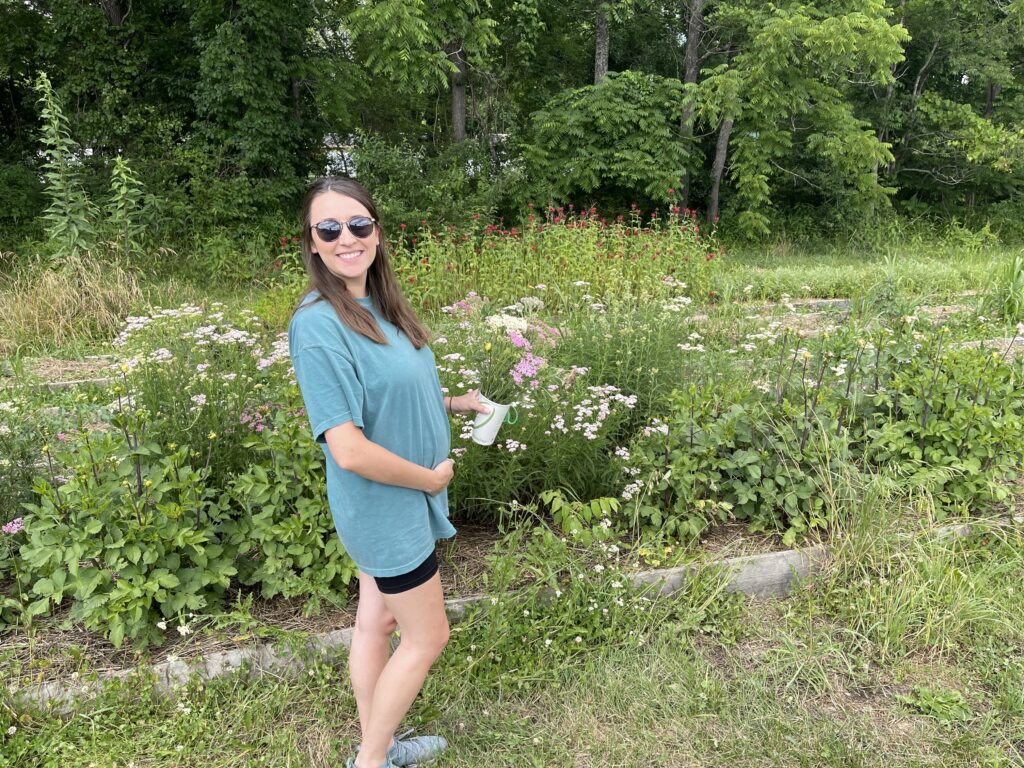 pregnant woman smiles at flying cloud farm in Fairview during asheville babymoon