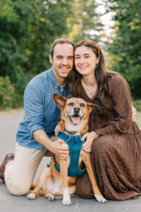 couple smiles with their dog on a walking trail at the Ecusta Market and Cafe in Hendersonville, NC with asheville family photographer rachel marie photography