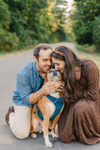 Couple kisses dog on a walking trail at the Ecusta Market and Cafe in Hendersonville, NC with family photographer Rachel Marie Photography 