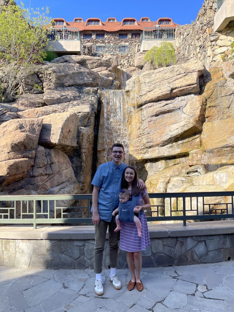 Mom, dad and baby smile in front of Omni Grove Park Inn in Asheville, NC