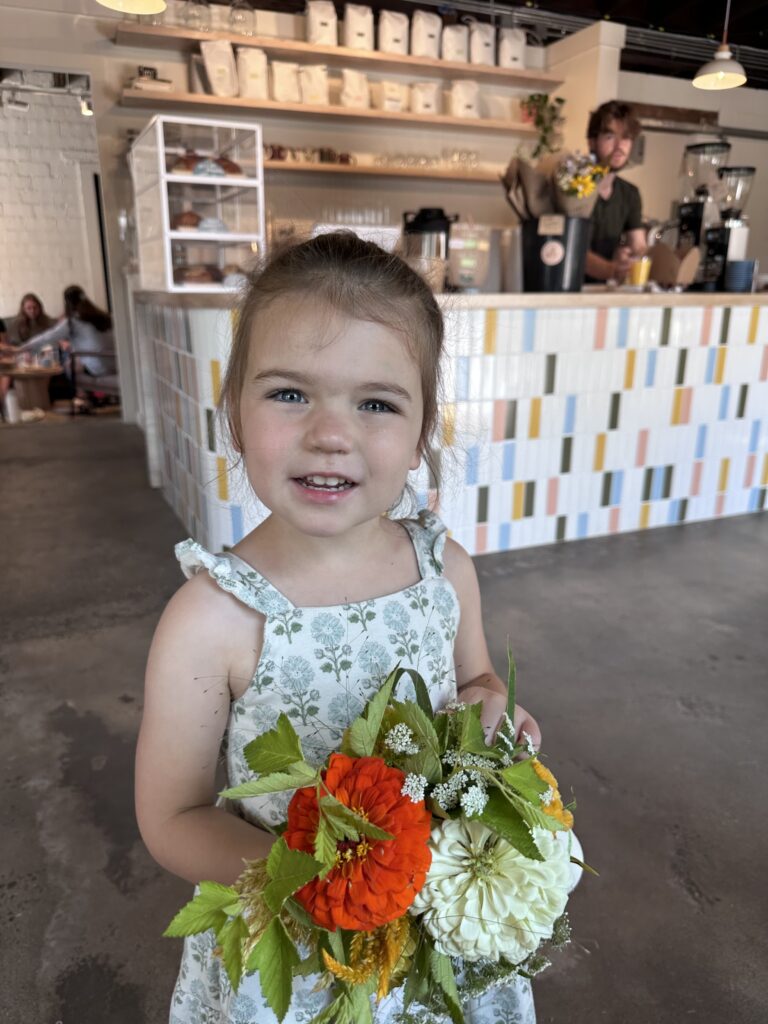 little girl holds locally made floral bouquet at Short Sleeves Coffee in Swannanoa, NC 