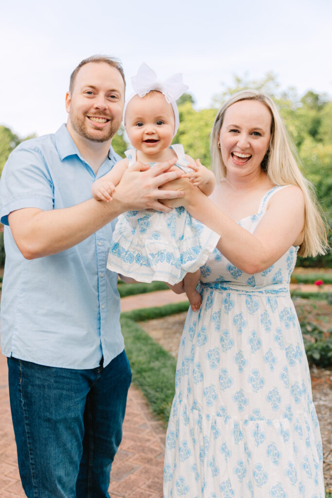 family plays with baby daughter in the rose gardens at the biltmore estate in asheville, nc during family photoshoot