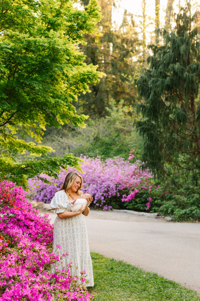 mom smiles down at newborn baby girl at the biltmore estate azalea newborn photo session in asheville, nc with asheville family photographer Rachel Marie Photography