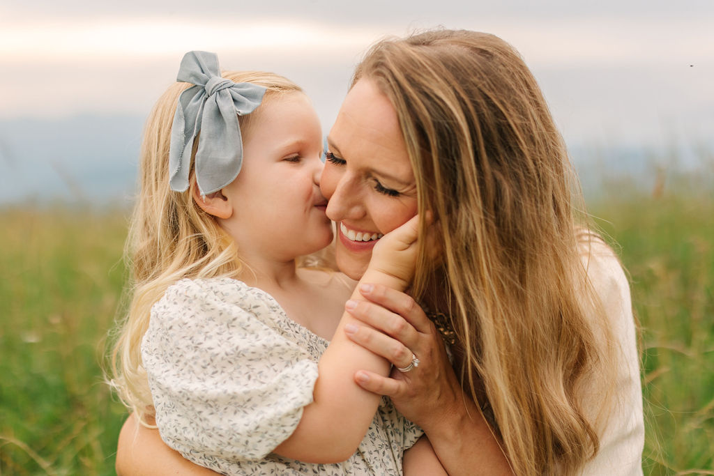 Toddler girl kisses her mom on the cheek at family photo session at Max Patch, NC with Asheville Family Photographer Rachel Marie Photography