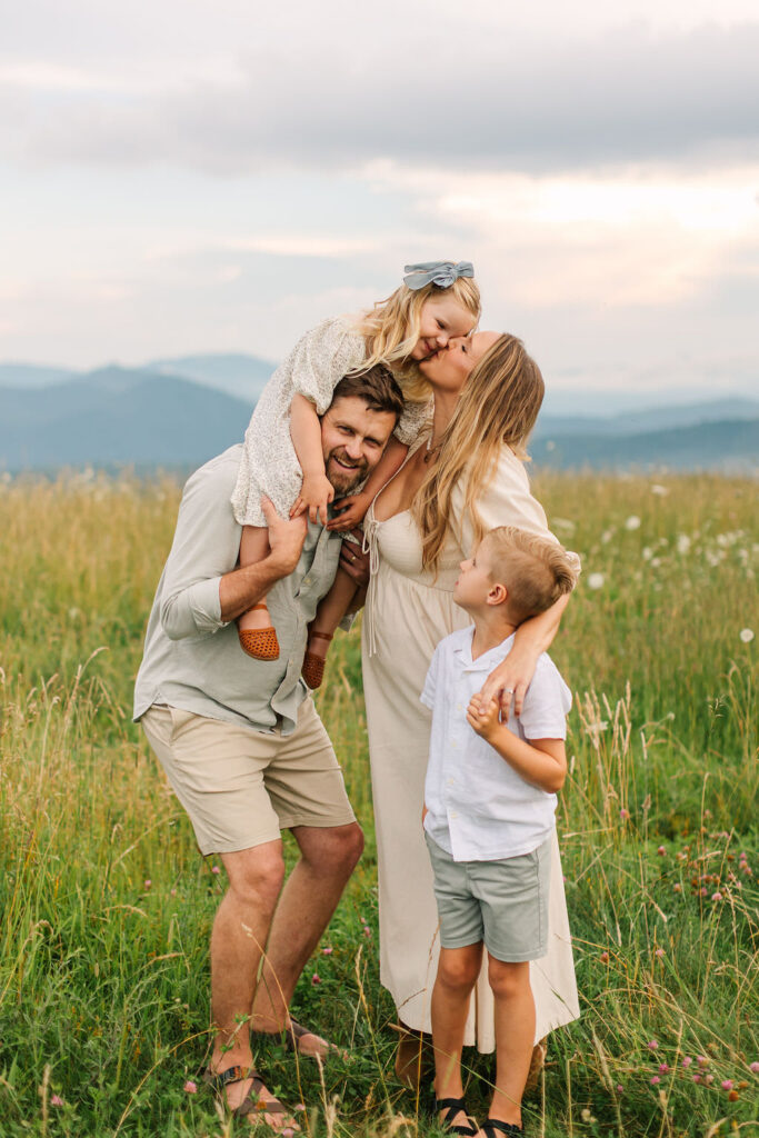 Family plays together and mom kisses daughter on cheek at family photo session at Max Patch, NC with Asheville Family Photographer Rachel Marie Photography