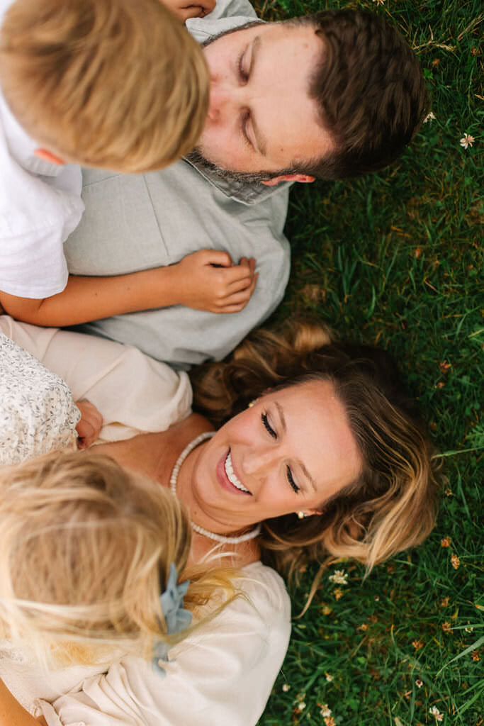 Family lays together in grassy field on a cloudy evening at Max Patch near Asheville, NC with family photographer Rachel Marie Photography