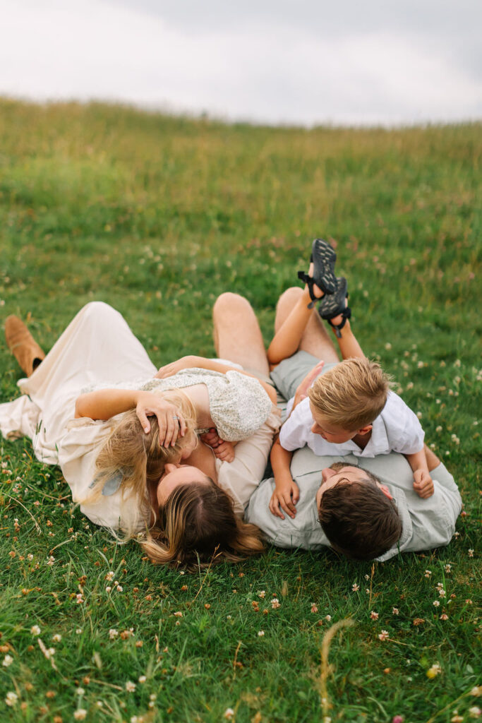 Family lays together in grassy field on a cloudy evening at Max Patch near Asheville, NC with family photographer Rachel Marie Photography