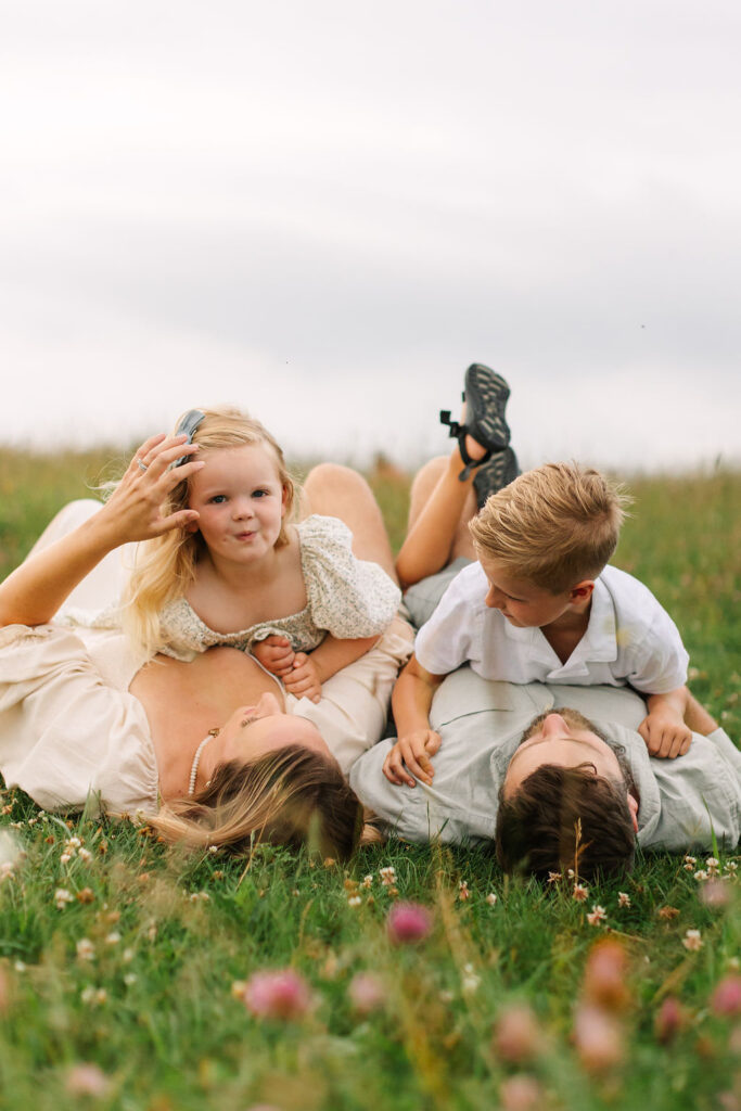 Family lays together in grassy field on a cloudy evening at Max Patch near Asheville, NC with family photographer Rachel Marie Photography
